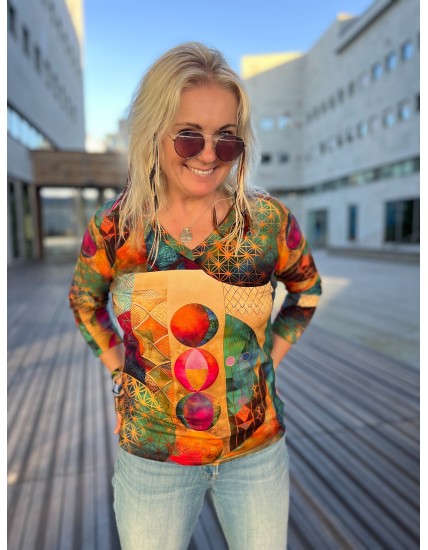 Kobieta w wielokolorowej bluzce z nadrukiem w kropki i okularach przeciwsłonecznych, stojąca na zewnątrz.