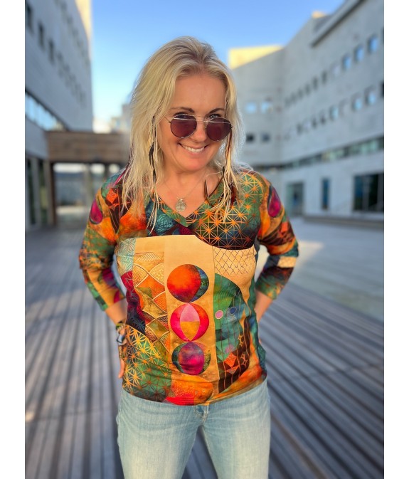 Kobieta w wielokolorowej bluzce z nadrukiem w kropki i okularach przeciwsłonecznych, stojąca na zewnątrz.