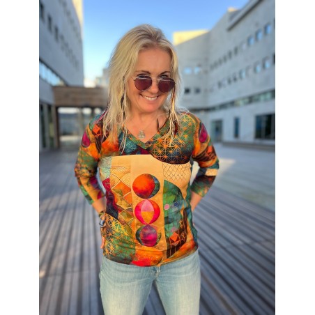 Kobieta w wielokolorowej bluzce z nadrukiem w kropki i okularach przeciwsłonecznych, stojąca na zewnątrz.